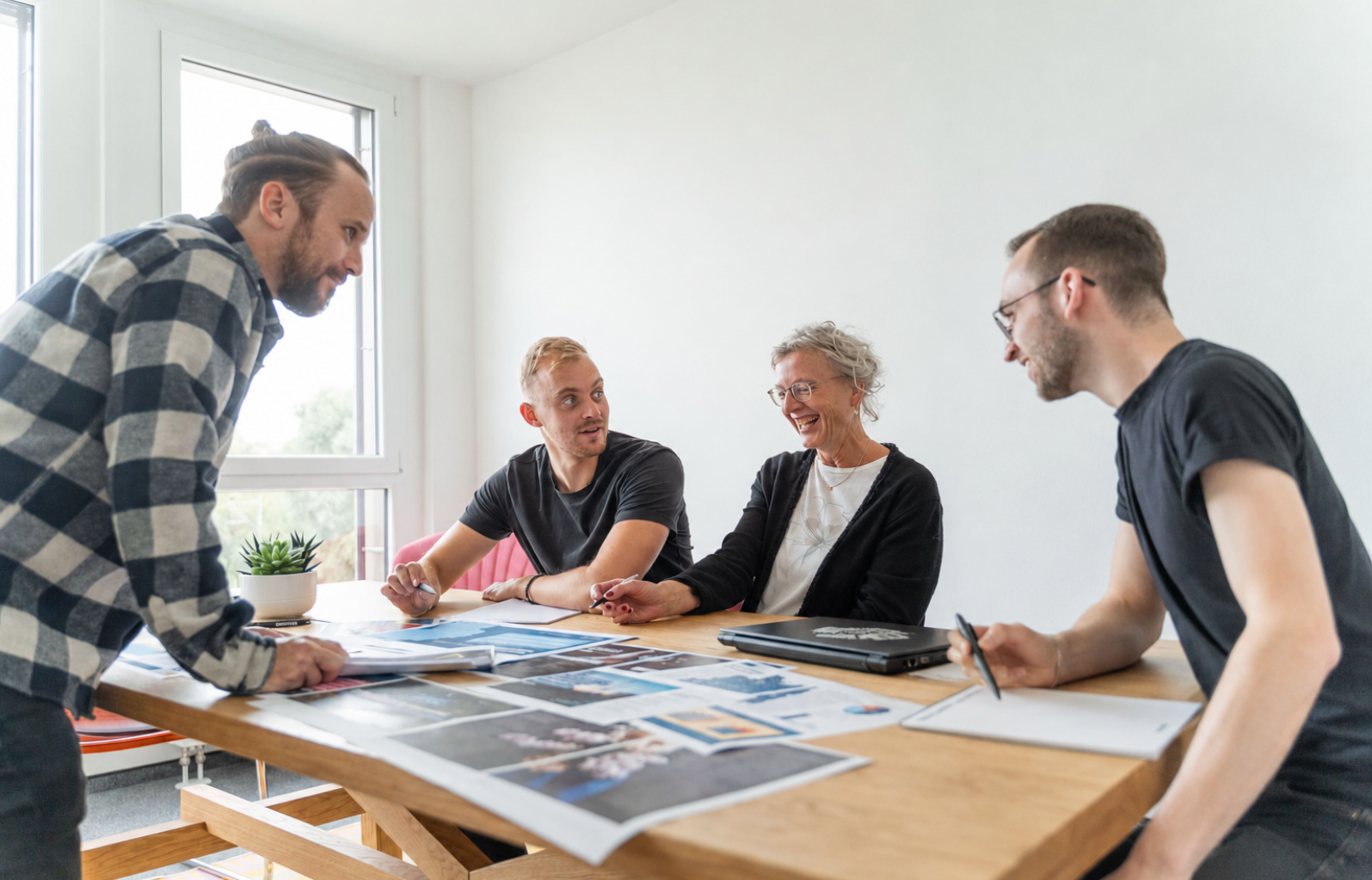 4 Mitarbeiter und eine Mitarbeiterin besprechen sich lachend miteinander